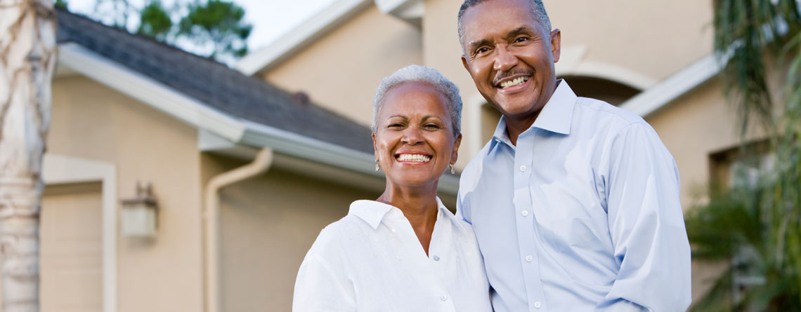 homeowner couple smiling in front of home